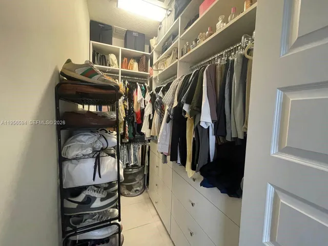 a view of walk in closet with clothes and shoes