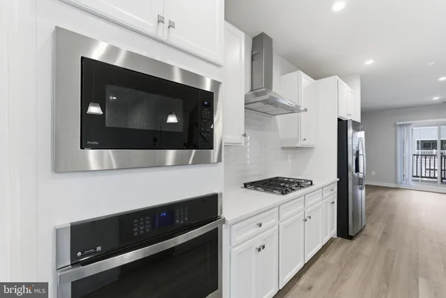 a kitchen with stainless steel appliances kitchen island granite countertop a stove a microwave a sink and cabinets