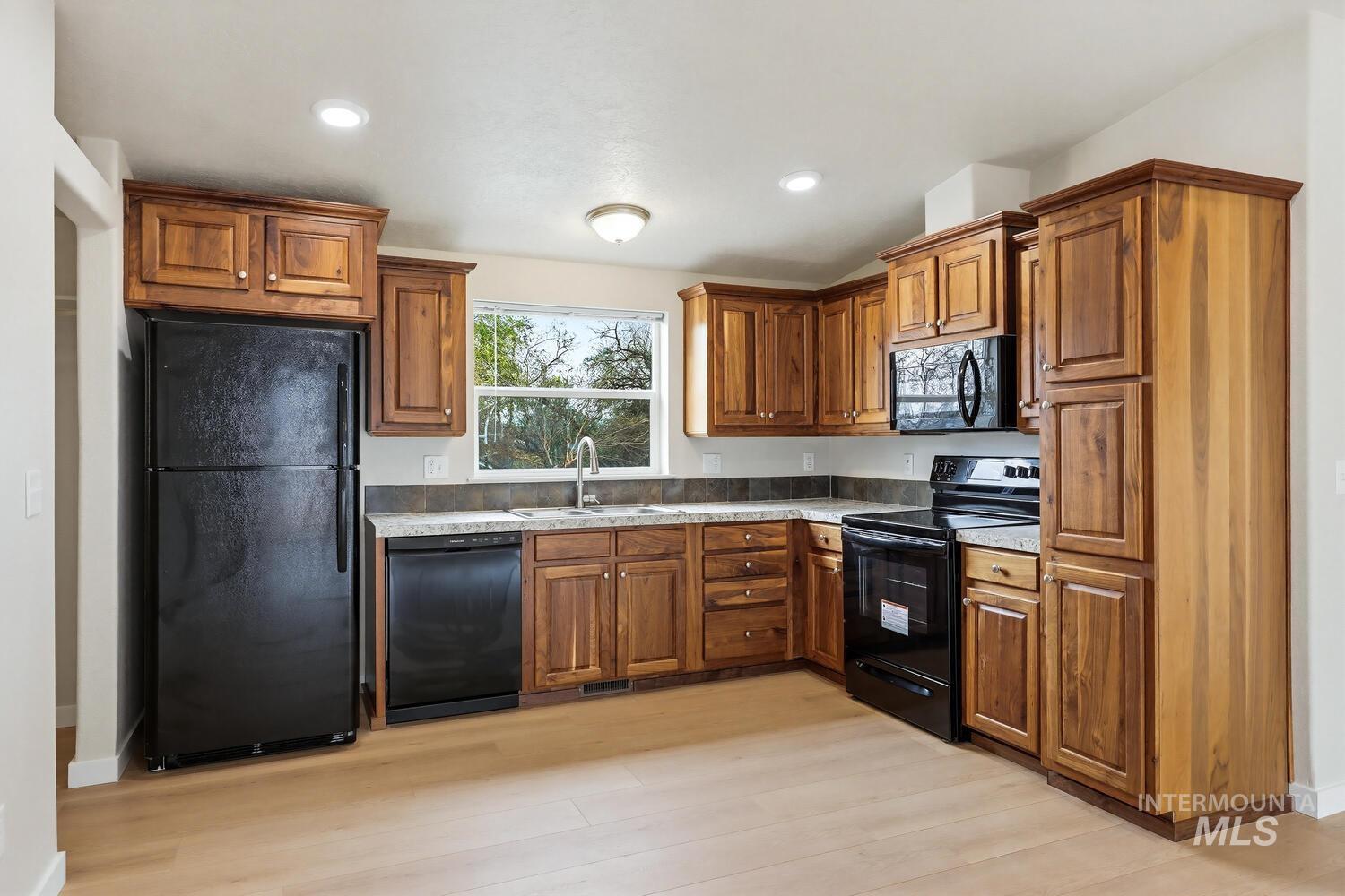 166 1st Street North Marsing, ID 83639 - Photo 11 of 37 Kitchen with wood finish cabinets, black appliances, light wood-style flooring, and recessed lighting