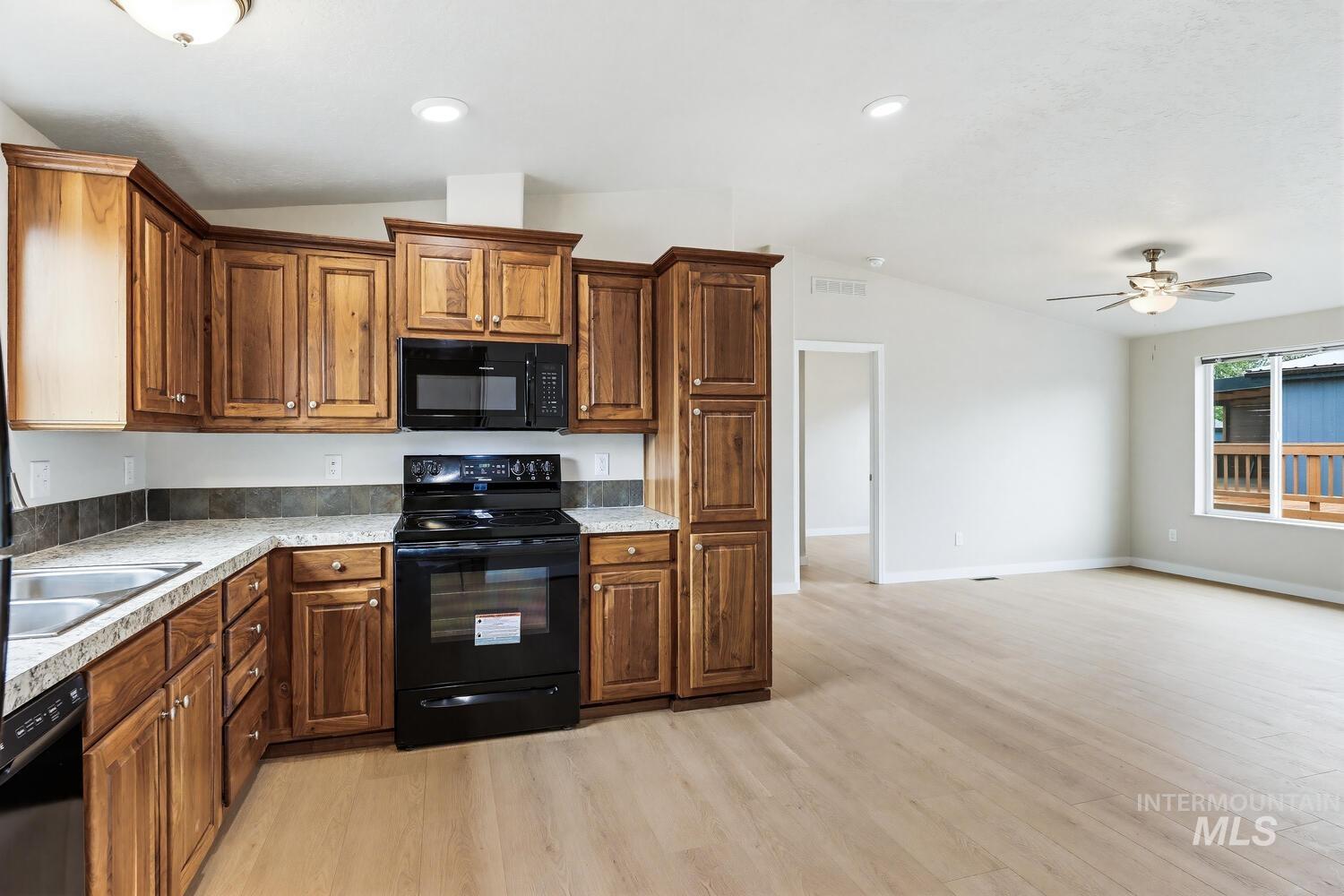 166 1st Street North Marsing, ID 83639 - Photo 13 of 37 Kitchen with black appliances, vaulted ceiling, light countertops, light wood-style flooring, and a ceiling fan
