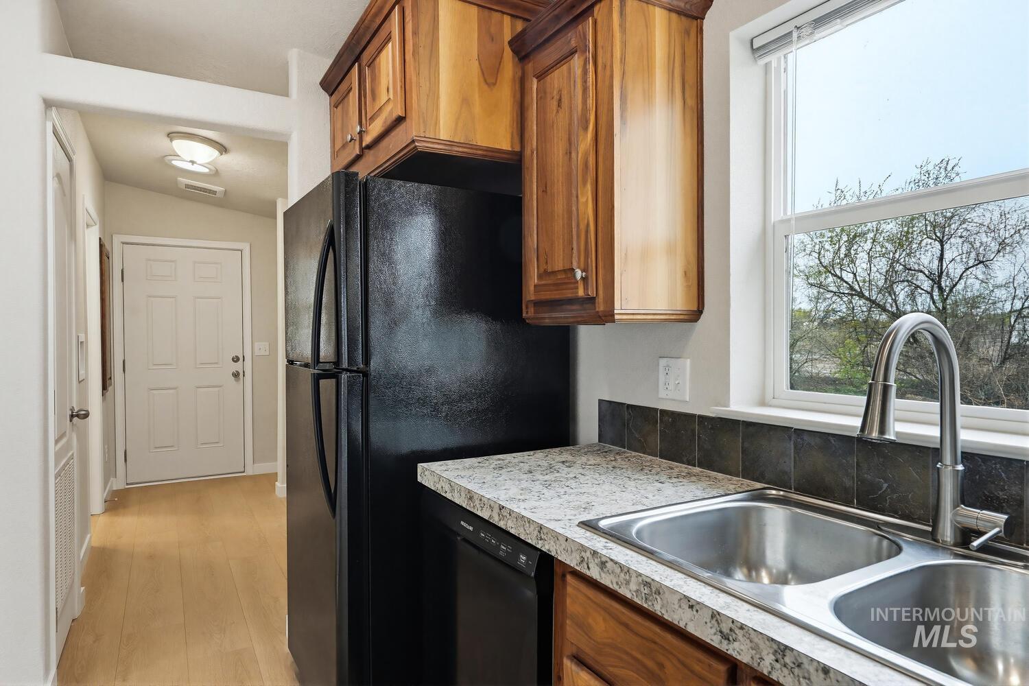 166 1st Street North Marsing, ID 83639 - Photo 14 of 37 Kitchen with wood finish cabinets, light countertops, light wood-style flooring, black appliances, and vaulted ceiling