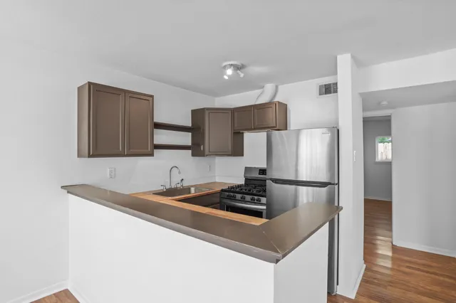 a kitchen with stainless steel appliances granite countertop a refrigerator a sink a stove a microwave and wooden floor