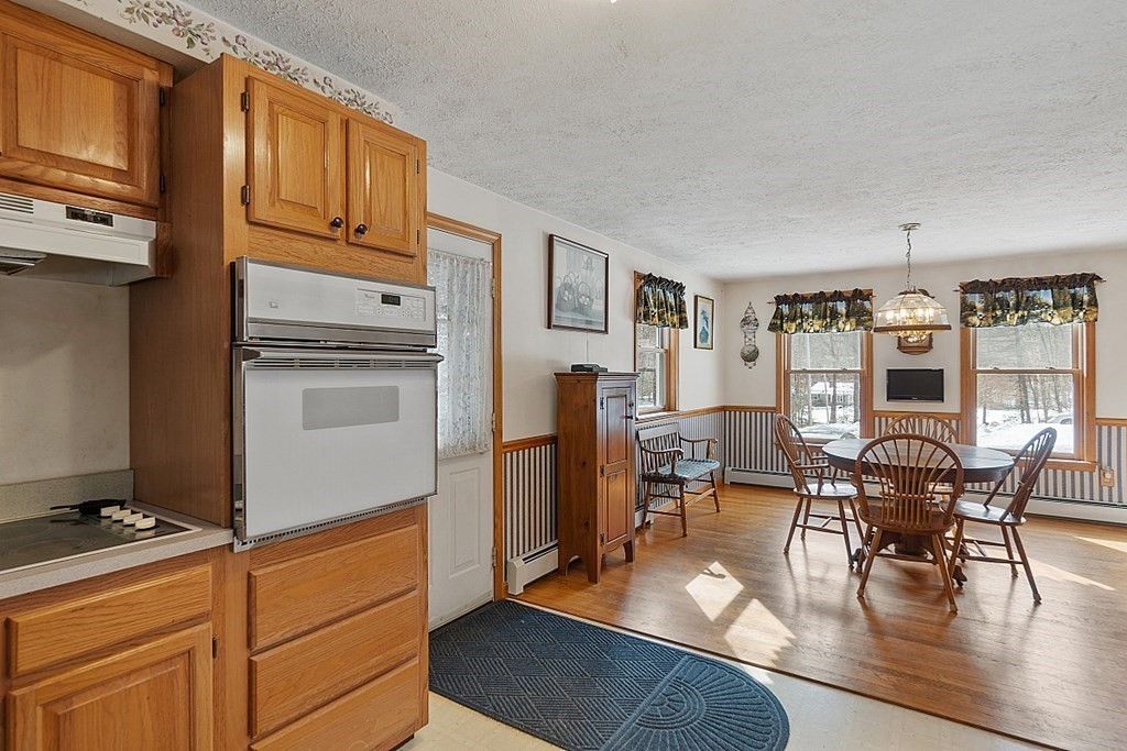 864 Foster Road Ashby, MA 01431 - Photo 12 of 41 a kitchen with stainless steel appliances granite countertop a stove top oven a refrigerator a dining table and chairs with wooden floor