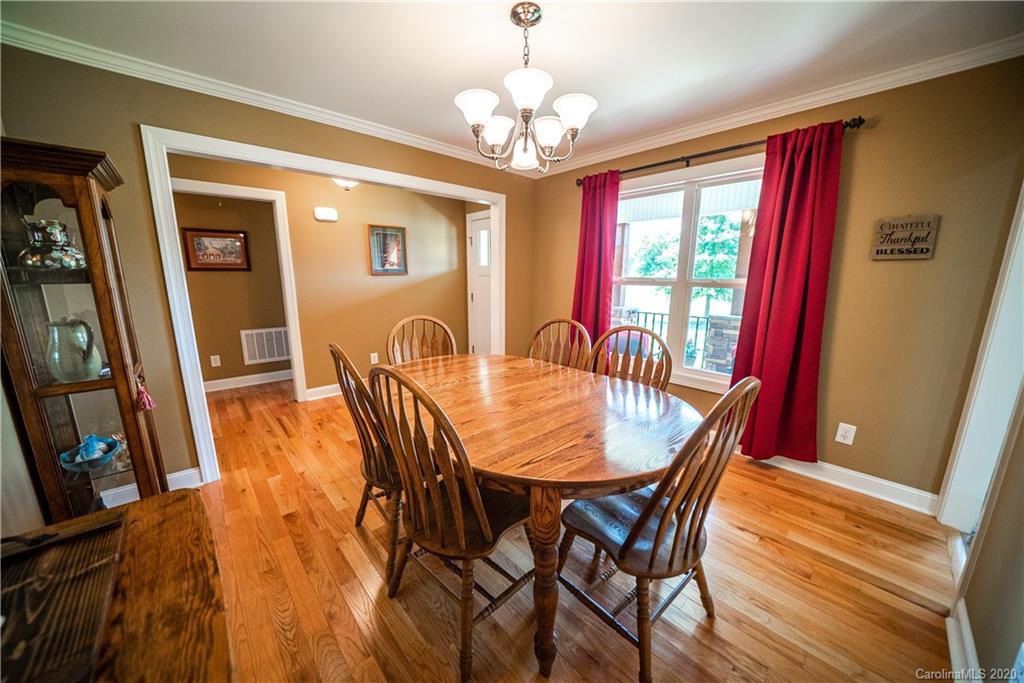 24376 Endy Road Albemarle, NC 28001 - Photo 17 of 27 a dining room with wooden floor a chandelier a wooden table and chairs