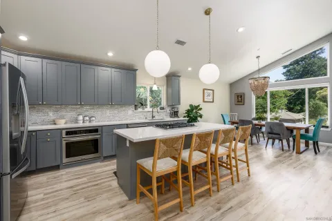 a kitchen with stainless steel appliances kitchen island granite countertop a stove a sink a dining table and chairs with wooden floor