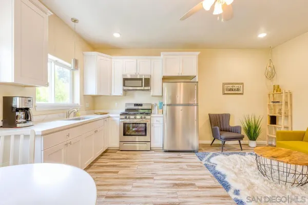 a kitchen with a refrigerator a stove a sink and white cabinets with wooden floor