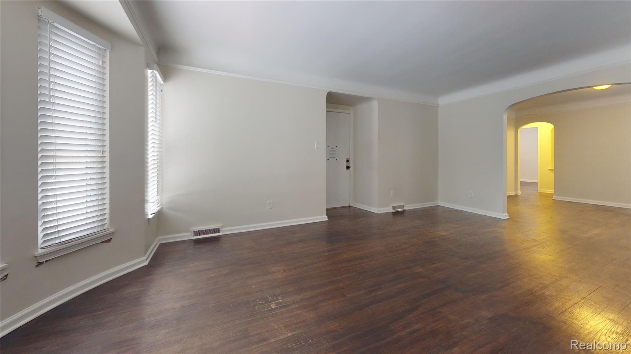 485 Neff Road Grosse Pointe, MI 48230 - Photo 4 of 11 Empty room with arched walkways, dark wood-style floors, and crown molding
