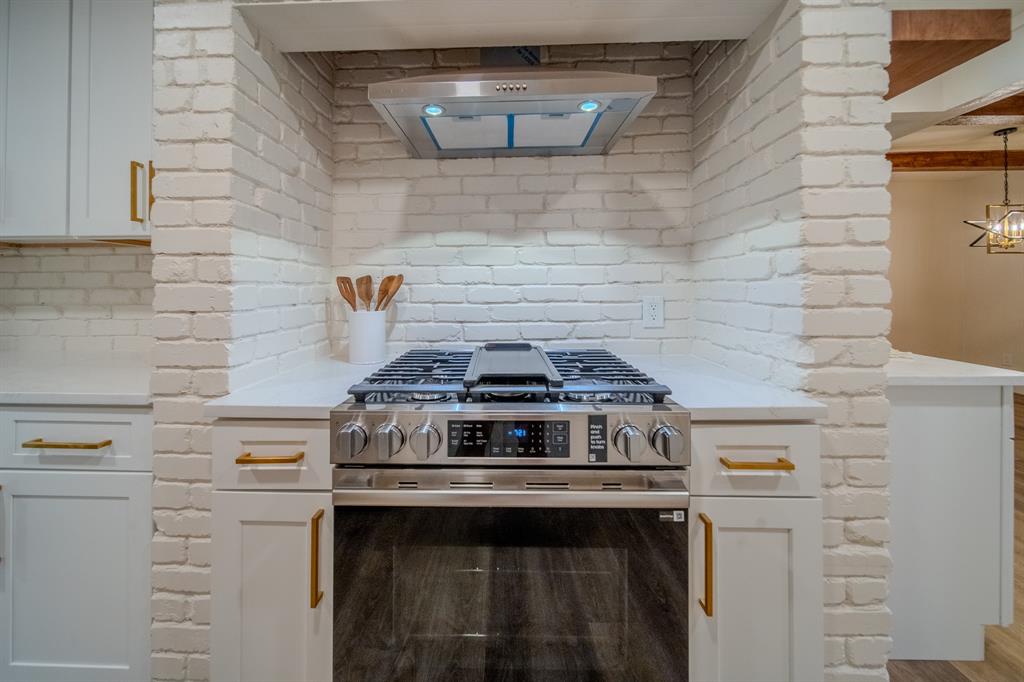 5125 Ashbrook Road Dallas, TX 75227 - Photo 18 of 34 Stainless steel range with a ventilation hood set within a white brick alcove