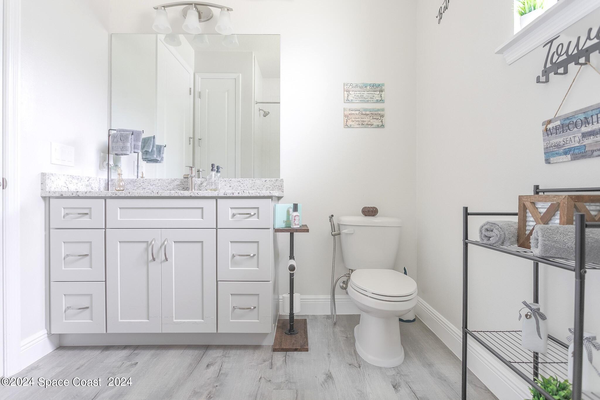 865 Hawks Ridge Court Northeast Palm Bay, FL 32905 - Photo 19 of 47 a bathroom with a granite countertop toilet sink and mirror