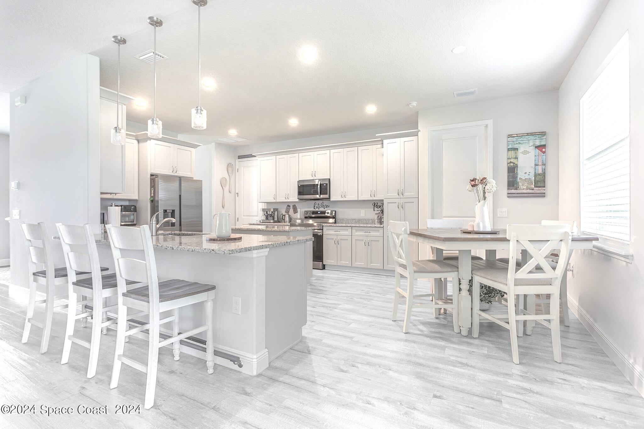 865 Hawks Ridge Court Northeast Palm Bay, FL 32905 - Photo 10 of 47 a dining room with stainless steel appliances kitchen island granite countertop a dining table chairs and view of living room