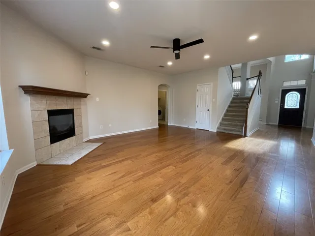 an empty room with wooden floor fireplace and windows