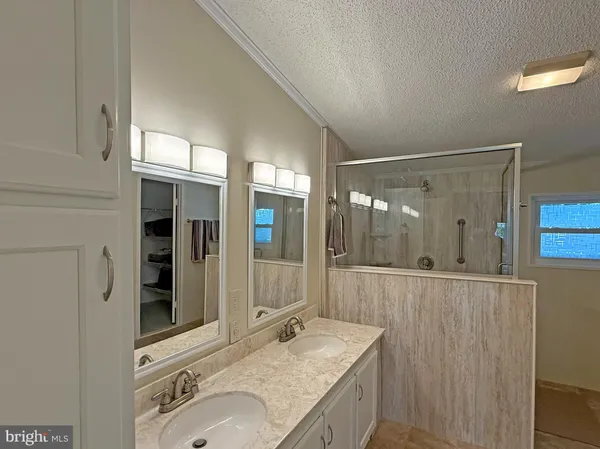 a bathroom with a granite countertop double vanity sink and mirror