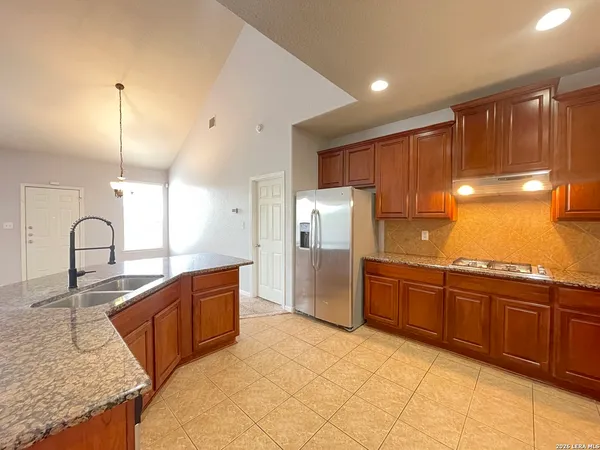 a kitchen with stainless steel appliances granite countertop a refrigerator a sink and wooden cabinets