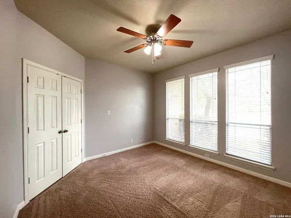 an empty room with windows and fan