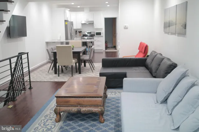 a living room with furniture a flat screen tv and kitchen view