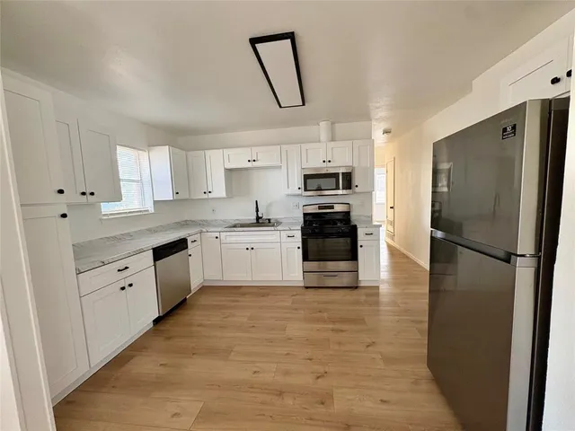 a kitchen with kitchen island white cabinets stainless steel appliances and a window