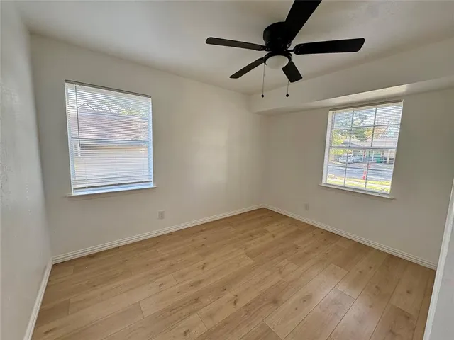 a view of an empty room with a window and a ceiling fan