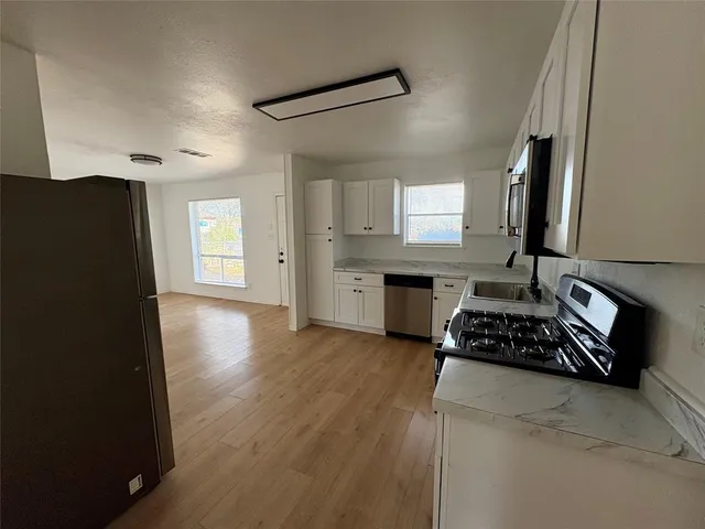 a kitchen with granite countertop a stove a sink dishwasher and a refrigerator with wooden floor