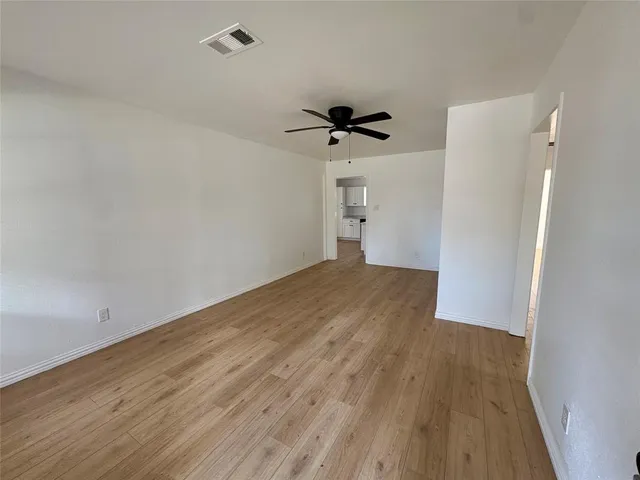 a view of a room with wooden floor and a ceiling fan