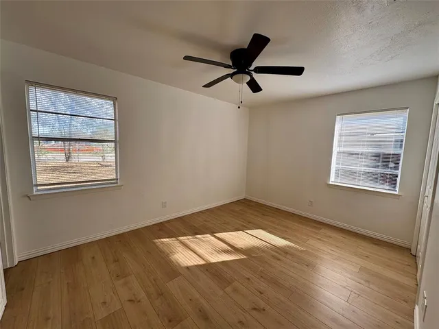 a view of empty room with wooden floor and window