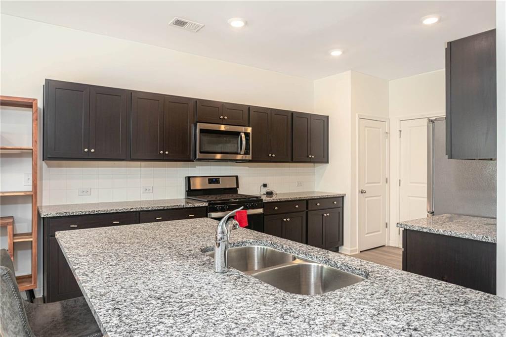 5760 Flint Lane Cumming, GA 30028 - Photo 11 of 39 a kitchen with kitchen island granite countertop a sink dishwasher stove and refrigerator with wooden floor