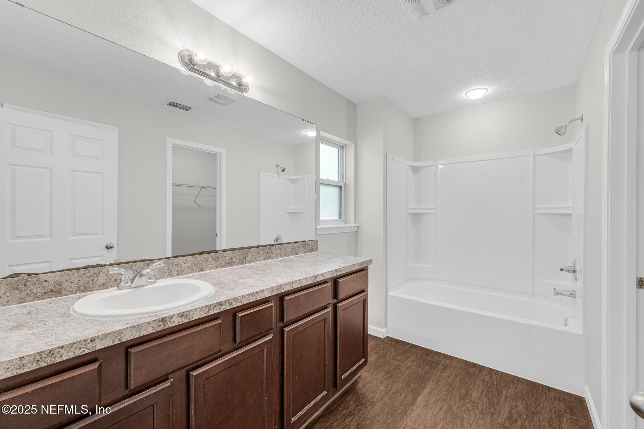 5120 Dugdale Road Jacksonville, FL 32210 - Photo 23 of 32 a bathroom with a granite countertop sink a mirror a bathtub and shower