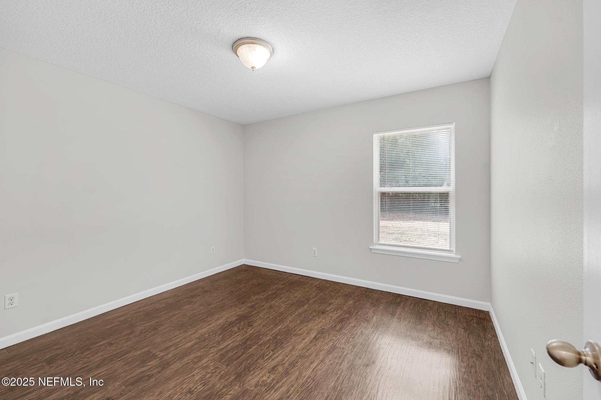 5120 Dugdale Road Jacksonville, FL 32210 - Photo 28 of 32 an empty room with wooden floor and windows