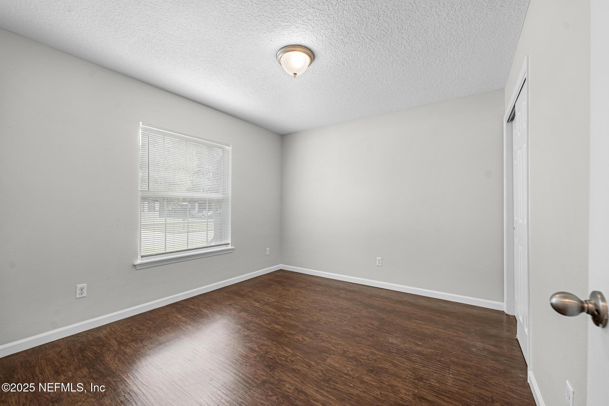 5120 Dugdale Road Jacksonville, FL 32210 - Photo 6 of 32 an empty room with wooden floor and windows