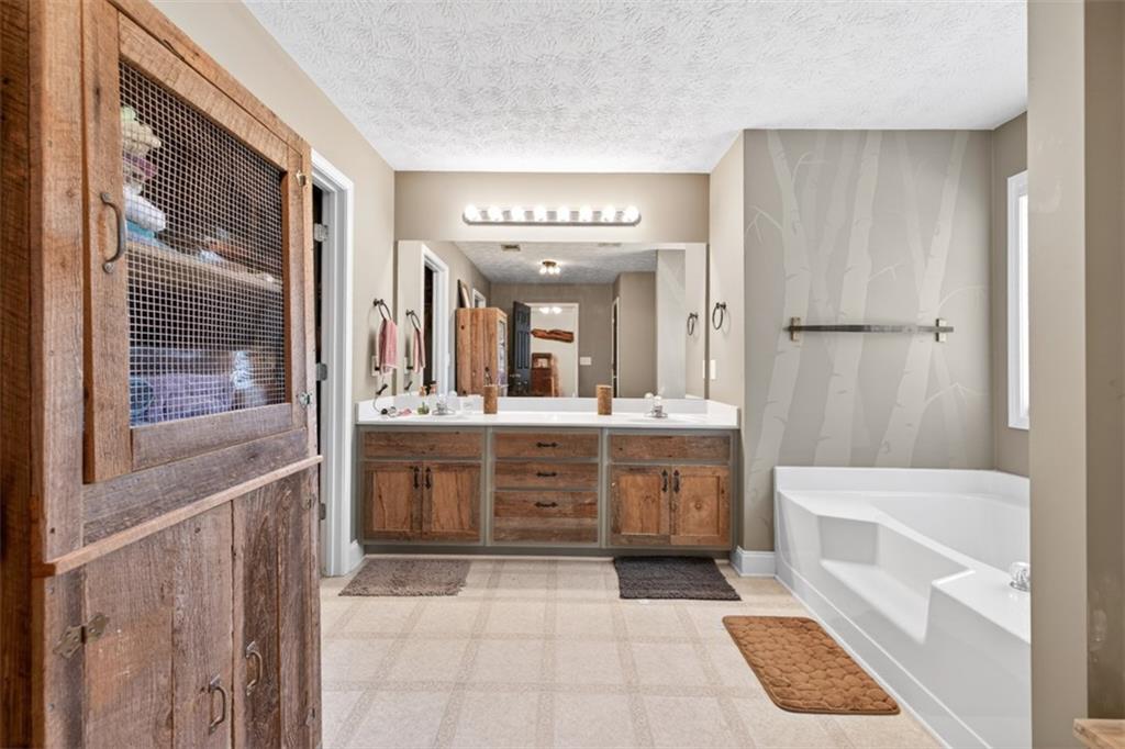 89 Katie Spring Lane Jefferson, GA 30549 - Photo 36 of 63 a bathroom with a double vanity sink a mirror a bathtub and shower