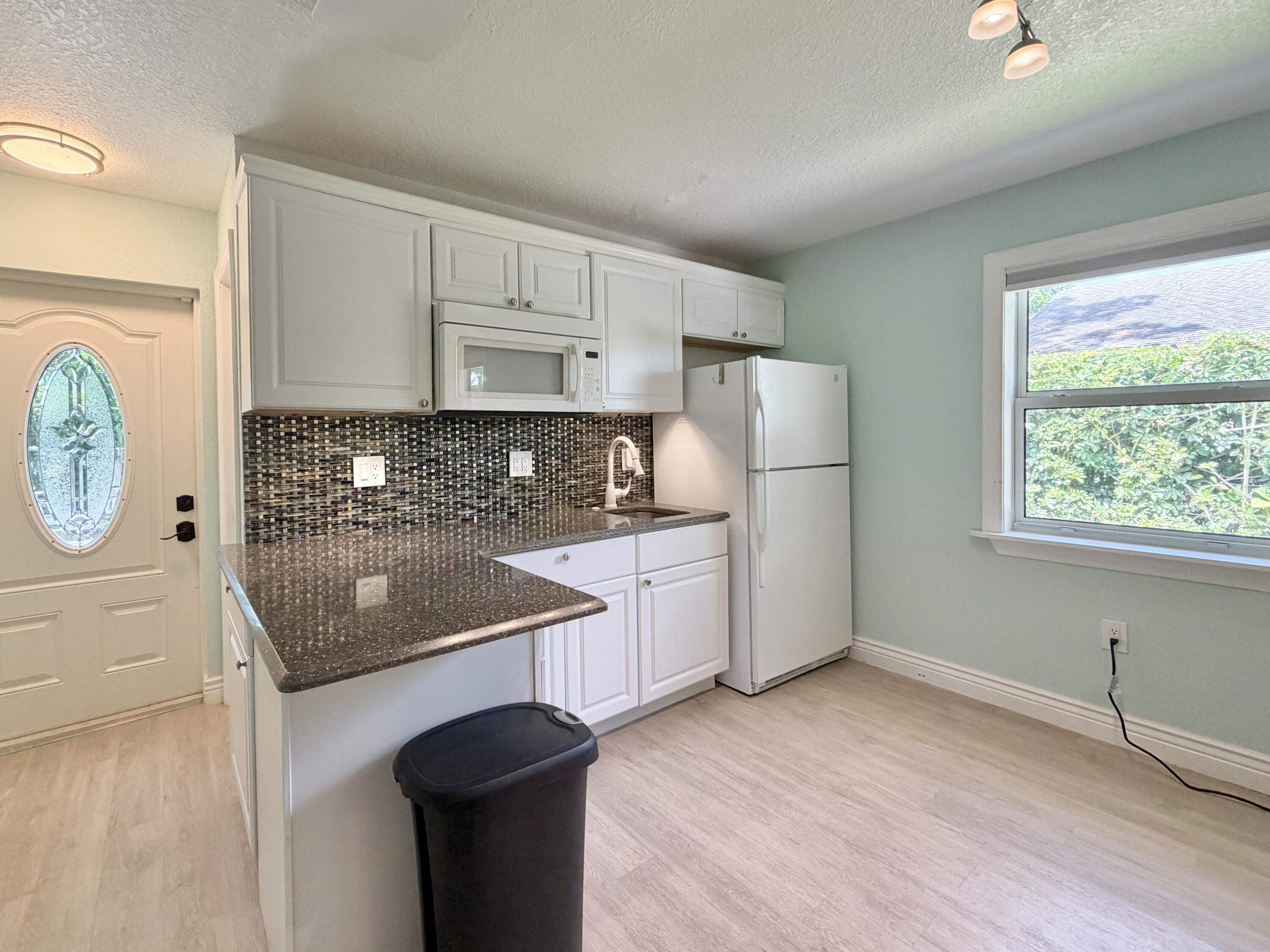 6100 Francis Street, Unit B Jupiter, FL 33458 - Photo 9 of 19 a kitchen with stainless steel appliances granite countertop a sink a stove a refrigerator cabinets and wooden floor