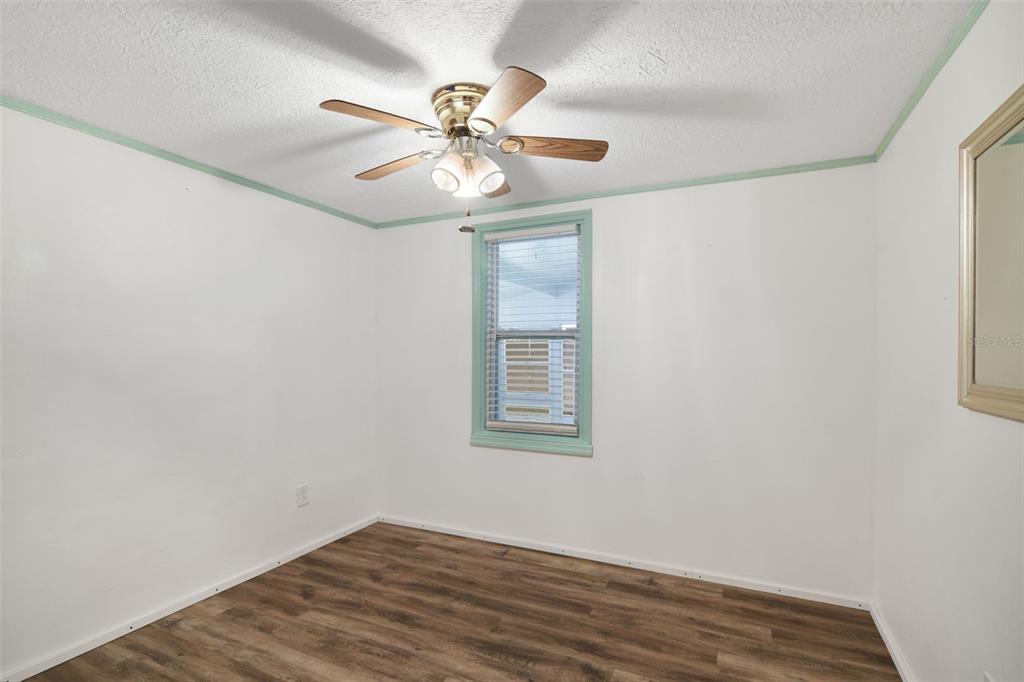 916 Fernald Street Edgewater, FL 32132 - Photo 11 of 27 an empty room with wooden floor fan and windows