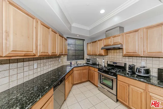 a kitchen with granite countertop a sink a stove and cabinets