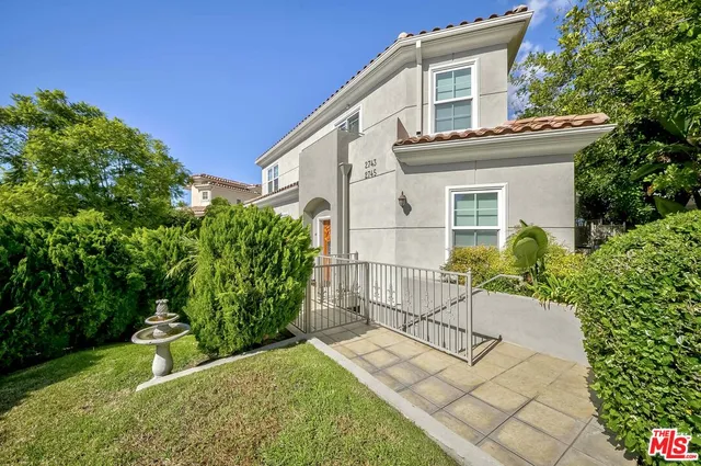 a view of a white house with a small yard and plants