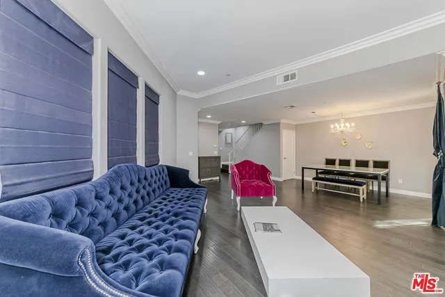 a living room with furniture and a dining table with kitchen countertops with wooden floor