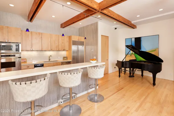 a kitchen with stainless steel appliances kitchen island granite countertop a table chairs in it and wooden floors