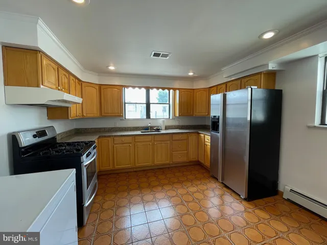 a kitchen with stainless steel appliances granite countertop a refrigerator a sink a stove top oven and cabinets