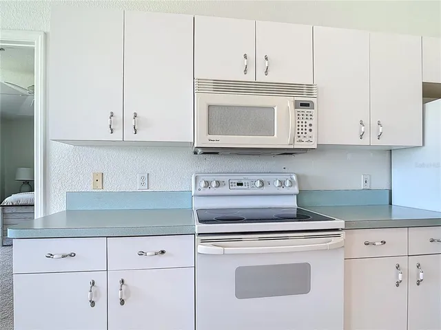 a kitchen with white cabinets and refrigerator