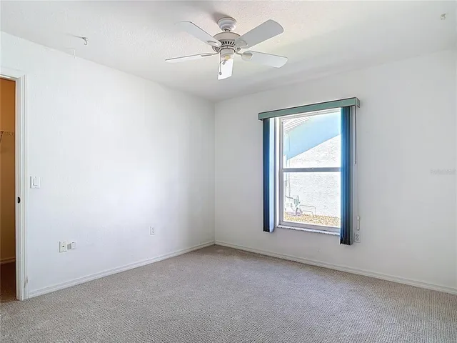 an empty room with a chandelier fan and closet area