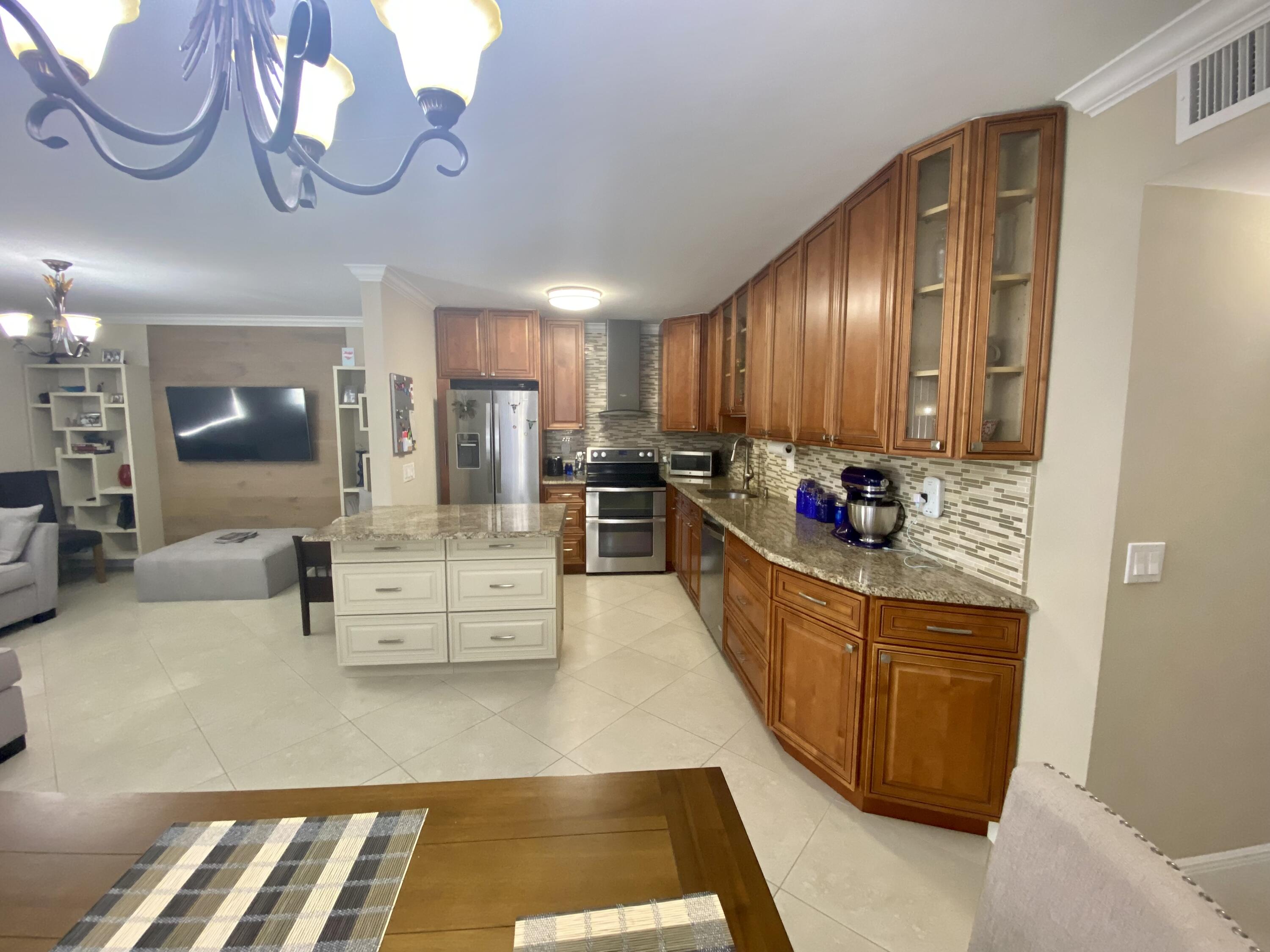 a large open kitchen with stainless steel appliances kitchen island granite countertop a stove and white cabinets