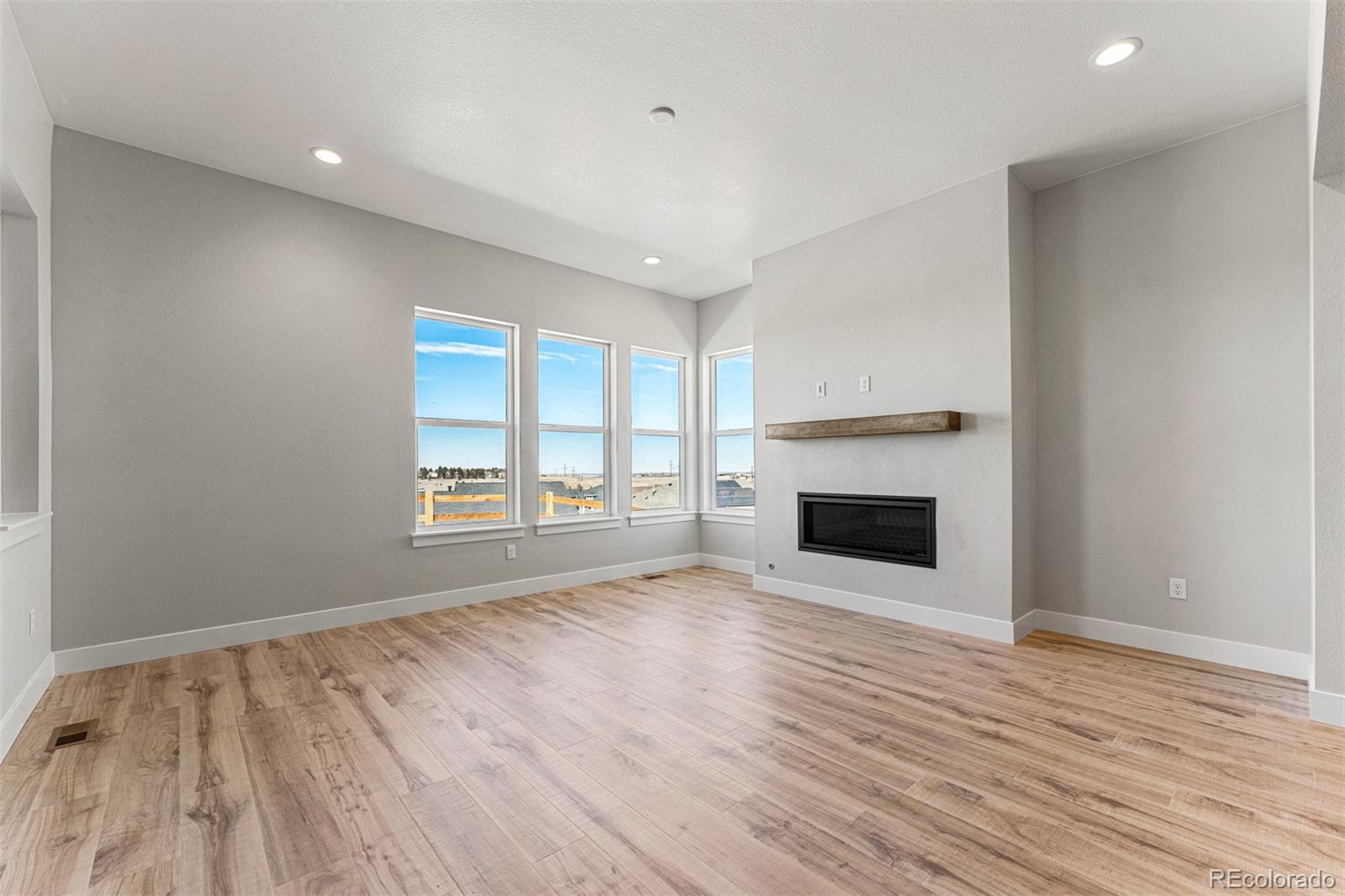 75 Clara Place Castle Pines, CO 80108 - Photo 9 of 39 wooden floor fireplace and windows in an empty room