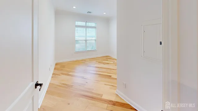 a view of empty room with wooden floor and fan
