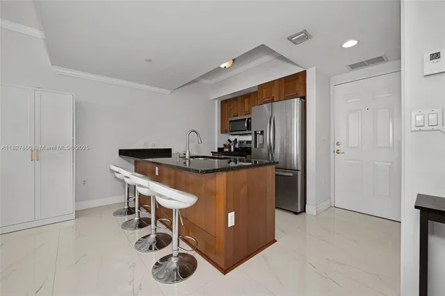 a kitchen with granite countertop a table chairs refrigerator and microwave