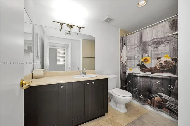 a bathroom with a granite countertop sink a toilet a mirror and shower