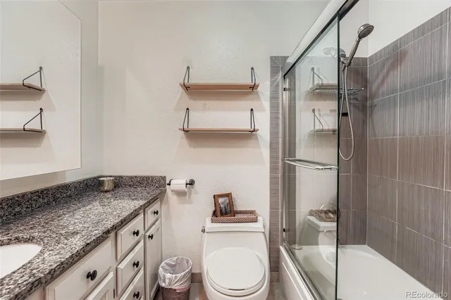 a bathroom with a granite countertop sink toilet and shower