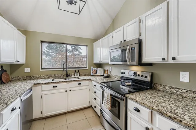 a kitchen with stainless steel appliances granite countertop white cabinets granite counter tops and a window