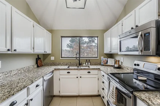 a kitchen with granite countertop a sink a stove and cabinets