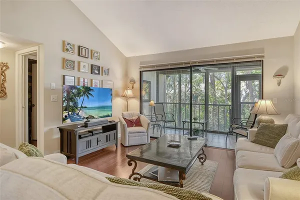 a living room with furniture a flat screen tv and a floor to ceiling window