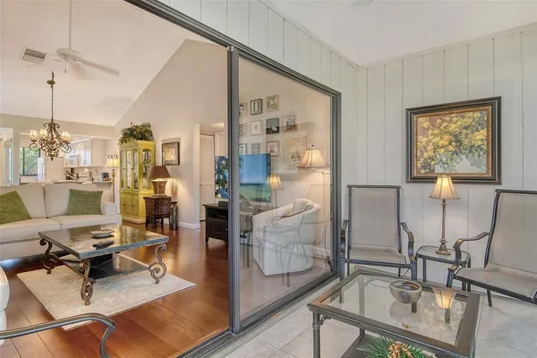 a living room with couches a coffee table and next to a window with wooden floor
