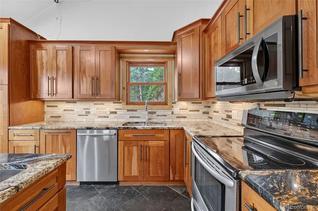 a kitchen with granite countertop a sink stove and cabinets