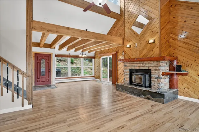 an empty room with wooden floor fireplace and windows